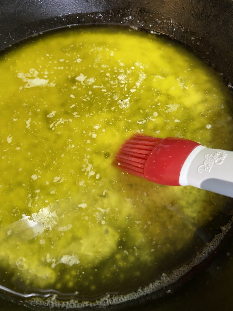 Melted butter in cast iron skillet, ready for brushing on pans
