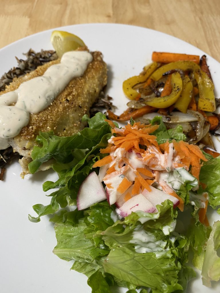 Wonderful plated meal with cornmeal-crusted fish over a bed of wild rice and a cashew sauce.  Served with sautéed vegetables and a salad with homemade ranch dressing. 