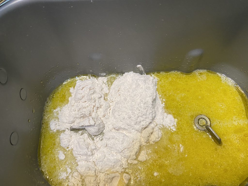 Liquid ingredients and some flour in bread machine pan